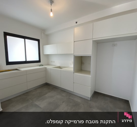 מטבח עם ארונות לבנים ומשטח עבודה